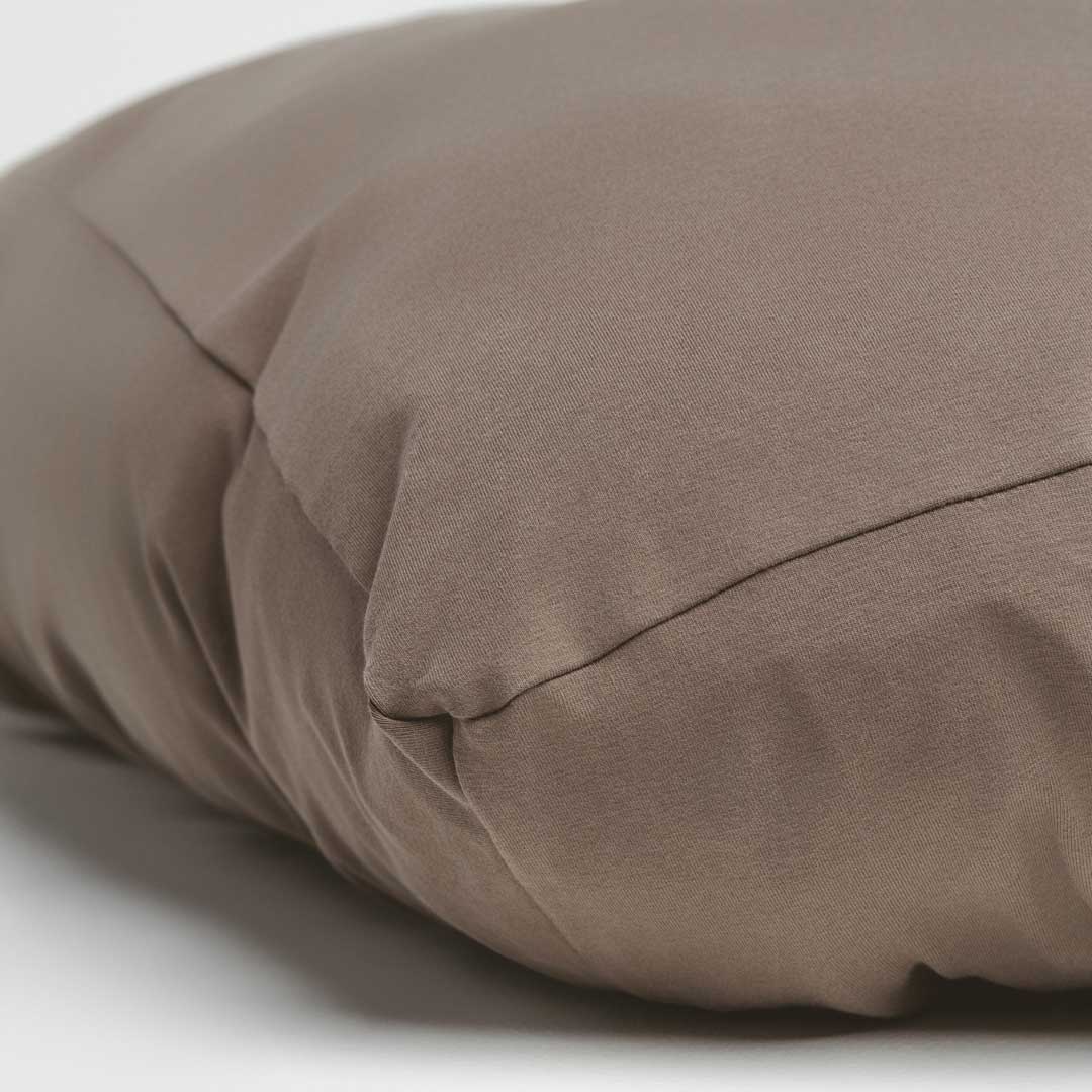 Close-up of a stretchy brown dog bed cover on a light background.
